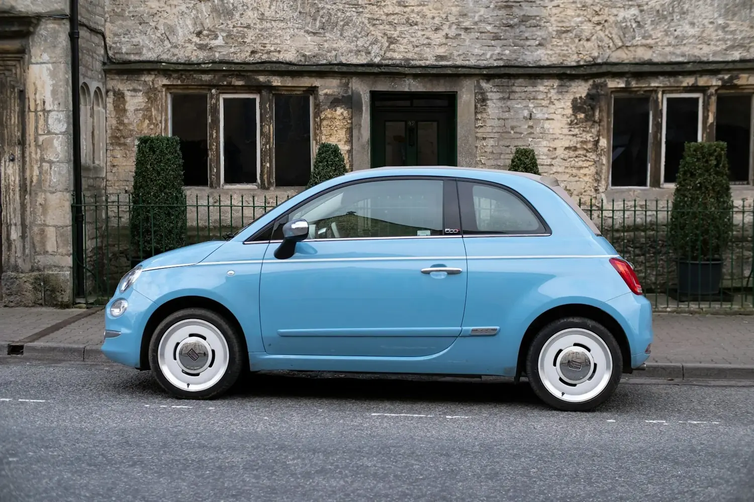 A small light-blue car parked on a village street